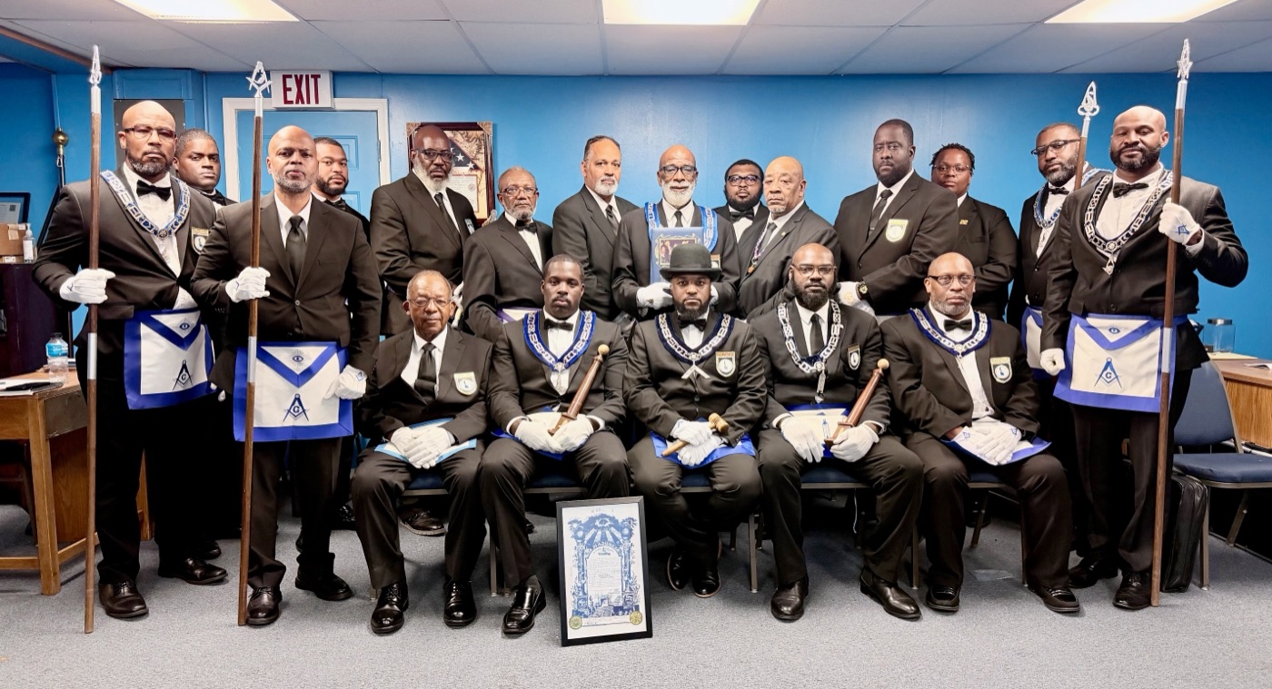 The officers and Brothers of Stone Square Lodge No. 22 in tuxedos, aprons, and white gloves, gathered in the Lodge room with the Lodge warrant